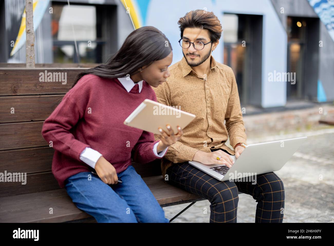 Schwarzes Mädchen und indischer Kerl mit digitalen Geräten Stockfoto