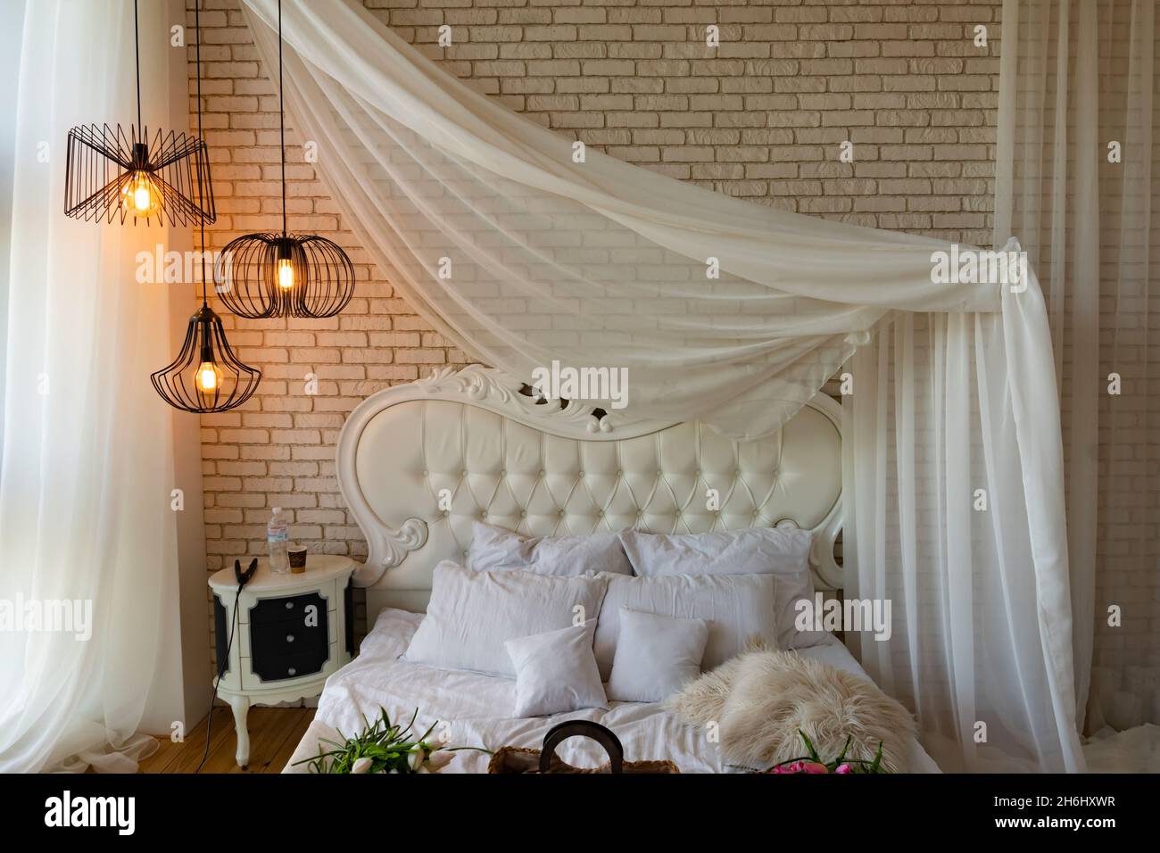 Romantisches Ambiente im Schlafzimmer mit weißen Möbeln und einem Himmelbett Stockfoto