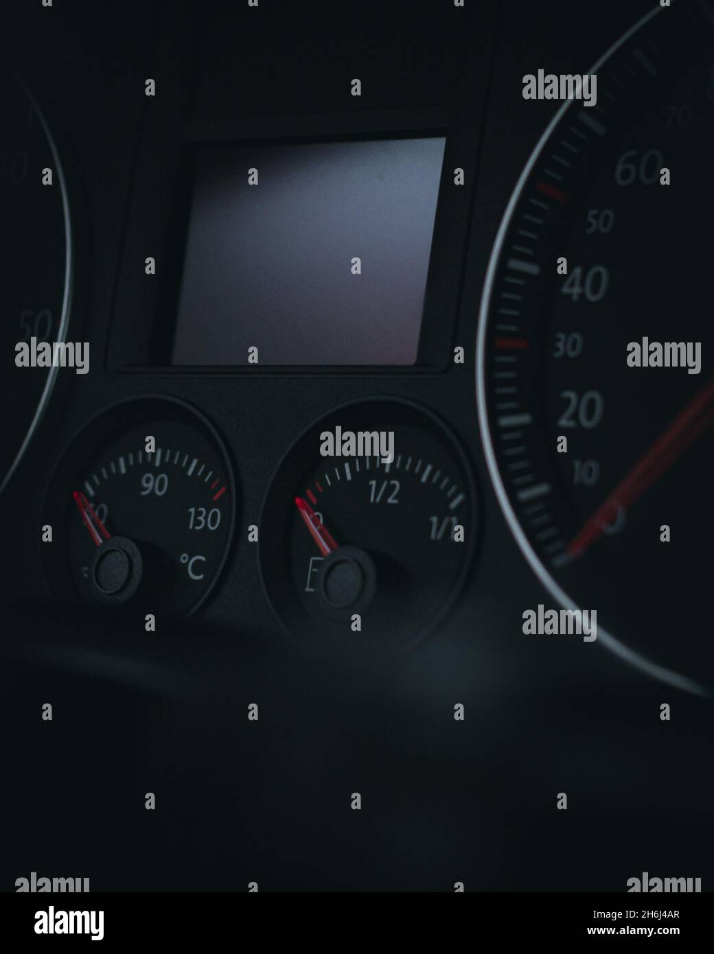 Vertikale Aufnahme von Tachometer und Tachometer eines Autos auf schwarzem Hintergrund Stockfoto