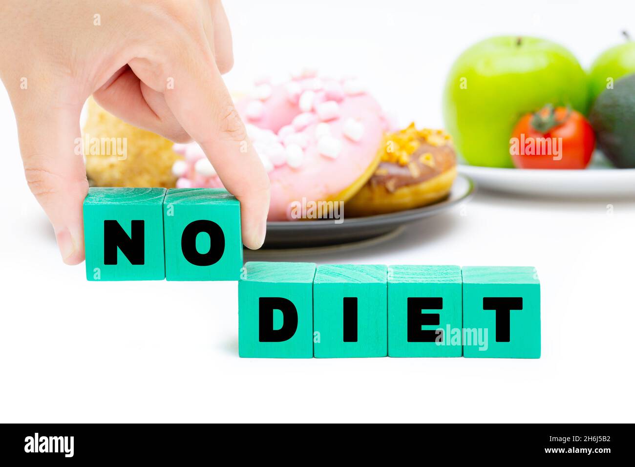 Text KEINE DIÄT aus Buchstabenblöcken vor einem schwarzen Teller mit Süßigkeiten und einem weißen Teller mit Obst und Gemüse. Gewichtsverlust Konzept. Stockfoto