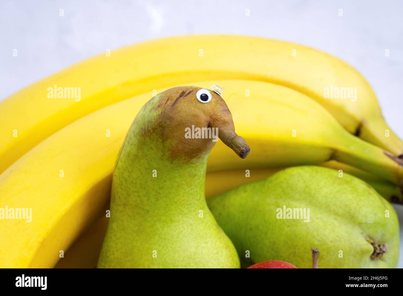 Porträt einer lustigen grünen Birne mit schönen Augen auf einem Obstteller Stockfoto