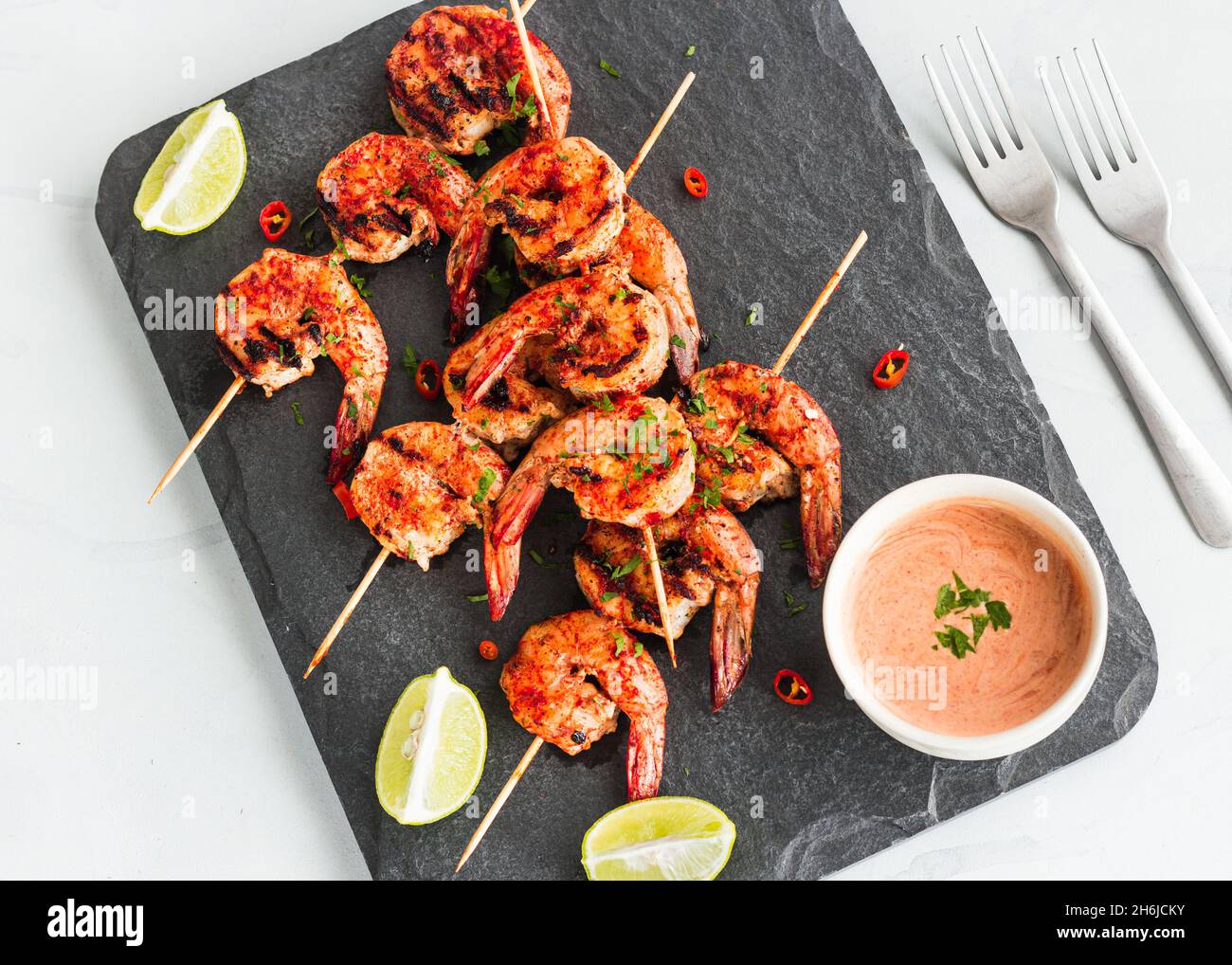 Piri Piri Gegrillte Garnelen auf den Spießen mit Zitrone und Conditioner auf einer Platte Top Down Flat Lay Photo Stockfoto