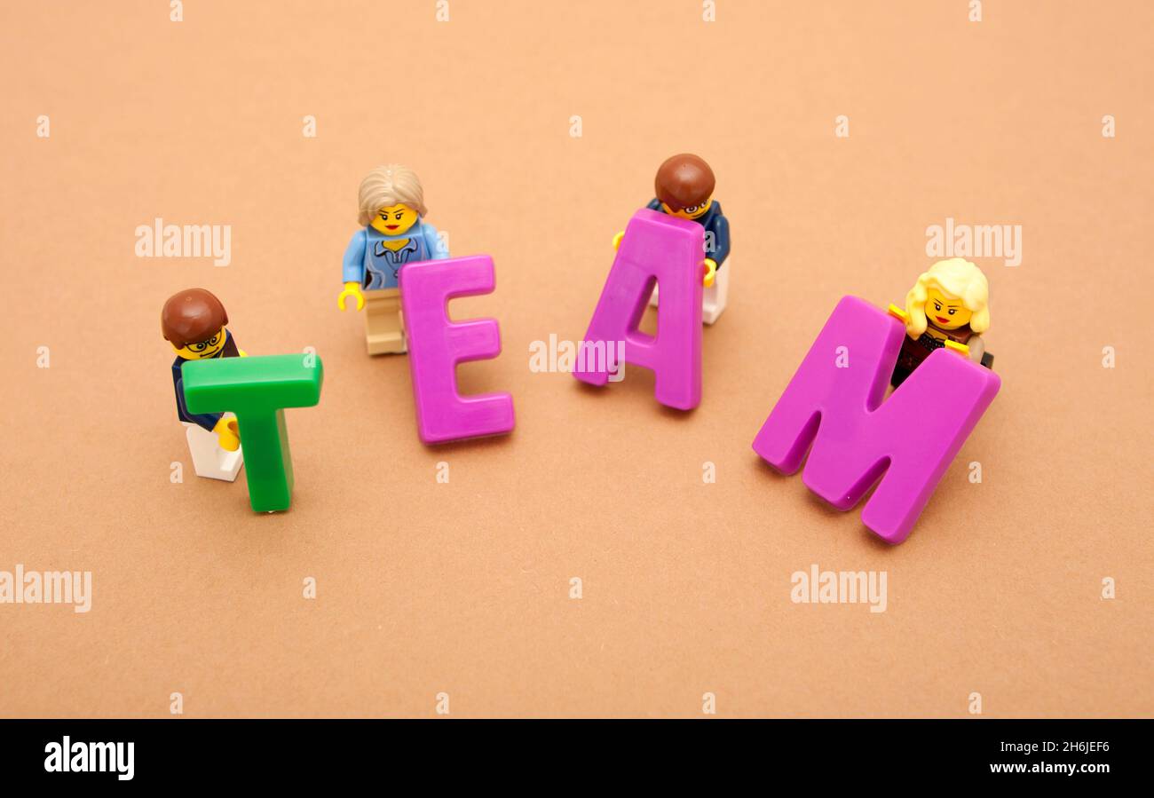 Eine Gruppe kleiner Spielzeugmänner und -Frauen, die aus großen Buchstaben das Wort „Team“ aufbauen Stockfoto