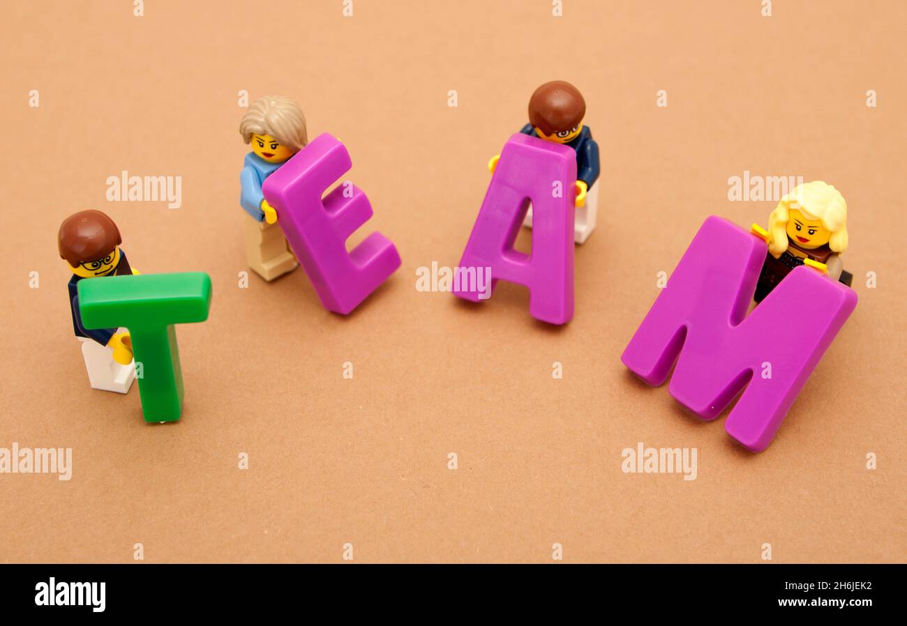 Eine Gruppe kleiner Spielzeugmänner und -Frauen, die aus großen Buchstaben das Wort „Team“ aufbauen Stockfoto