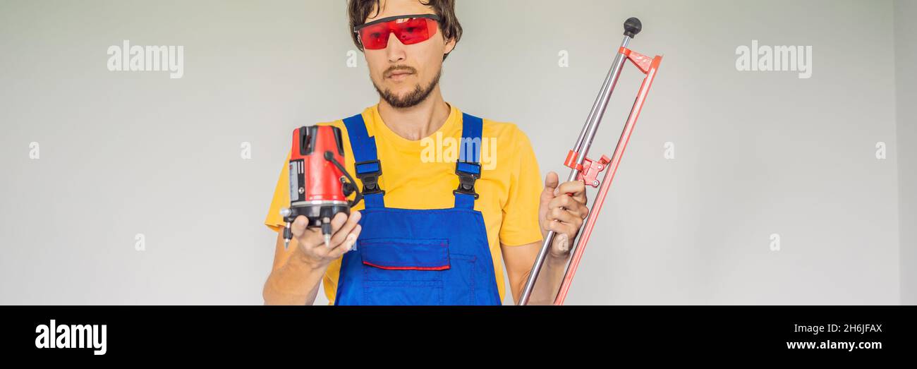 Ein Fliesenleger, ein Fliesenspezialist, hält einen Fliesenschneider in seinen Händen, EIN LANGFORMATIGES BANNER Stockfoto