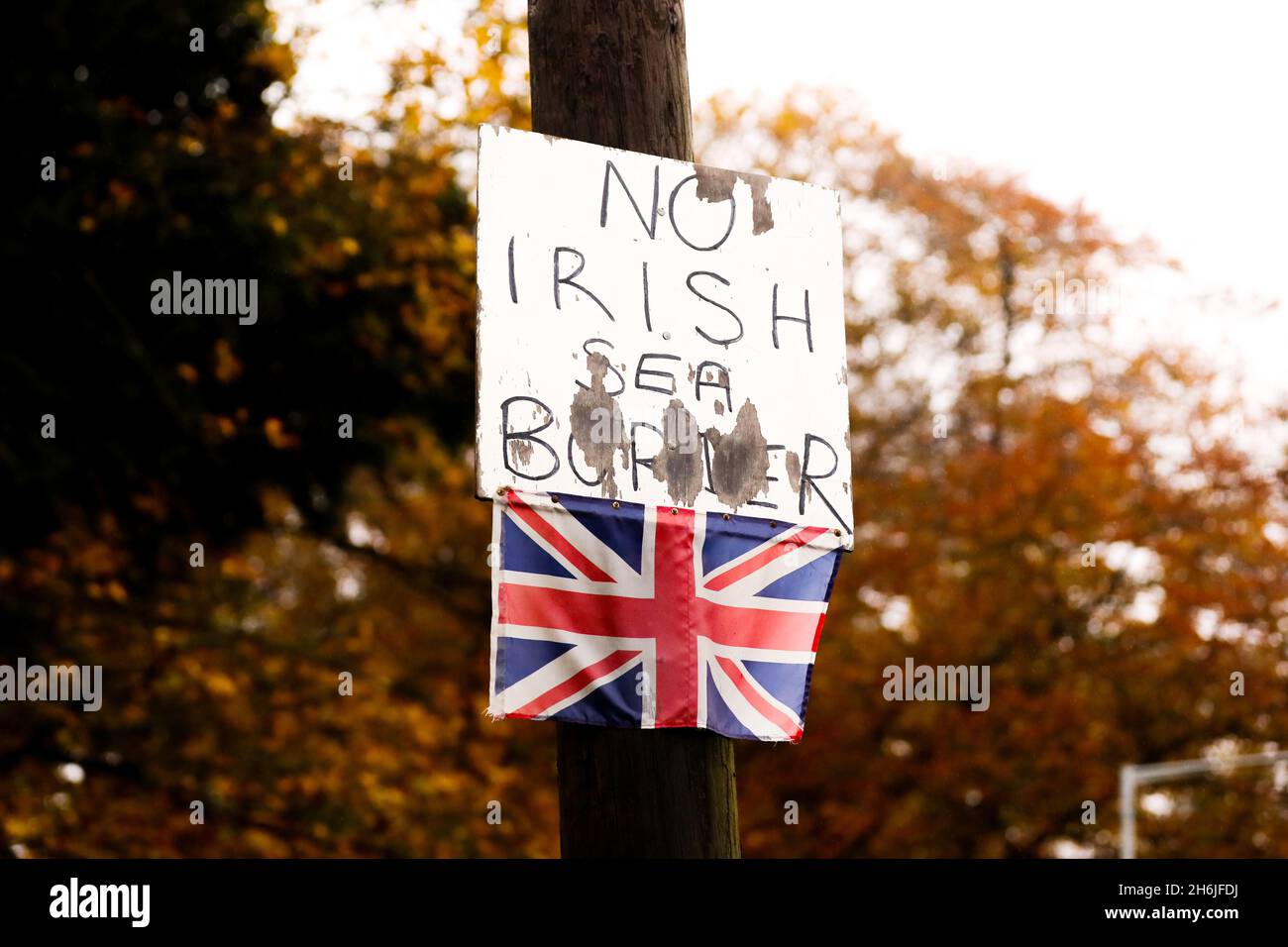 Ein Plakat gegen die irische Grenze und eine kleine Unionsflagge, die an einem Laternenpfahl in Bangor, Nordirland, angebracht sind, um gegen das Protokoll von Nordirland zu bestehen. Stockfoto