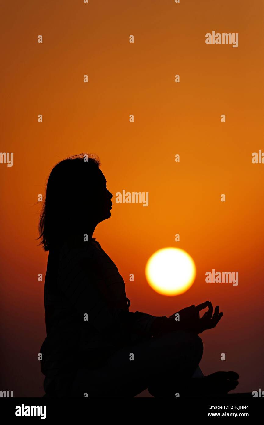 Frau, die Yoga-Pose und Meditation bei Sonnenuntergang als Konzept für Ruhe und Entspannung praktiziert, Vereinigte Arabische Emirate, Mittlerer Osten Stockfoto