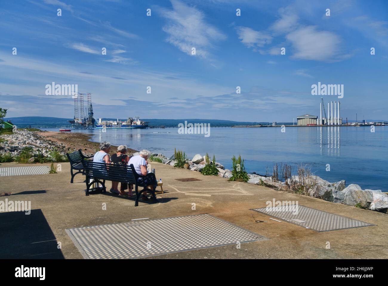 Damen-Picknick, Blick nach Norden über Cromarty Firth zur Nigg Bay, von Cromarty Village, Black Isle, schöner klarer sonniger Tag, friedlich, ruhig, Ölbohrinseln Stockfoto