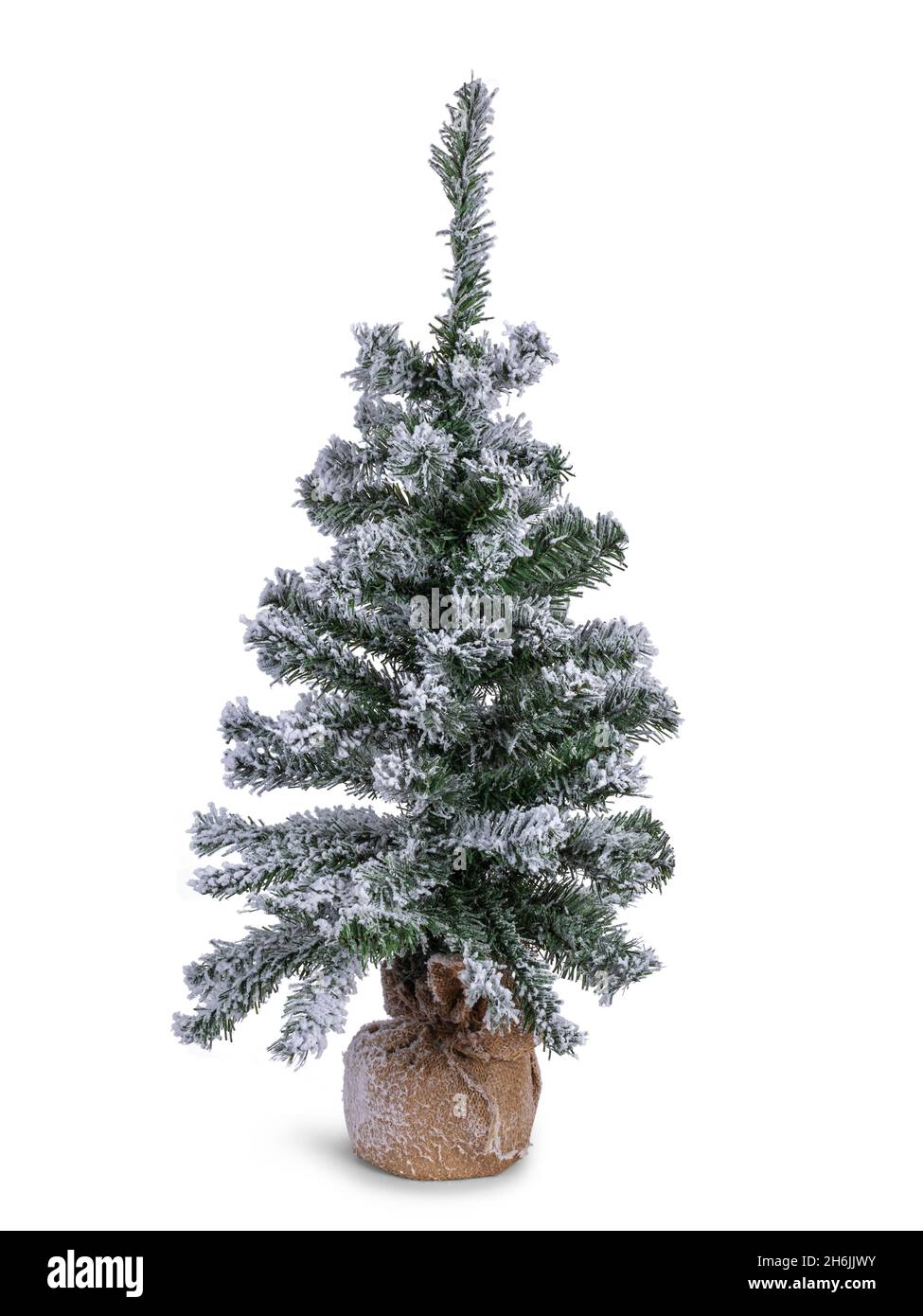 Gefälschter Weihnachtsbaum mit gefälschtem Schnee auf Ästen. Wurzeln in braunem Material bedeckt. Isoliert auf weißem Hintergrund. Stockfoto