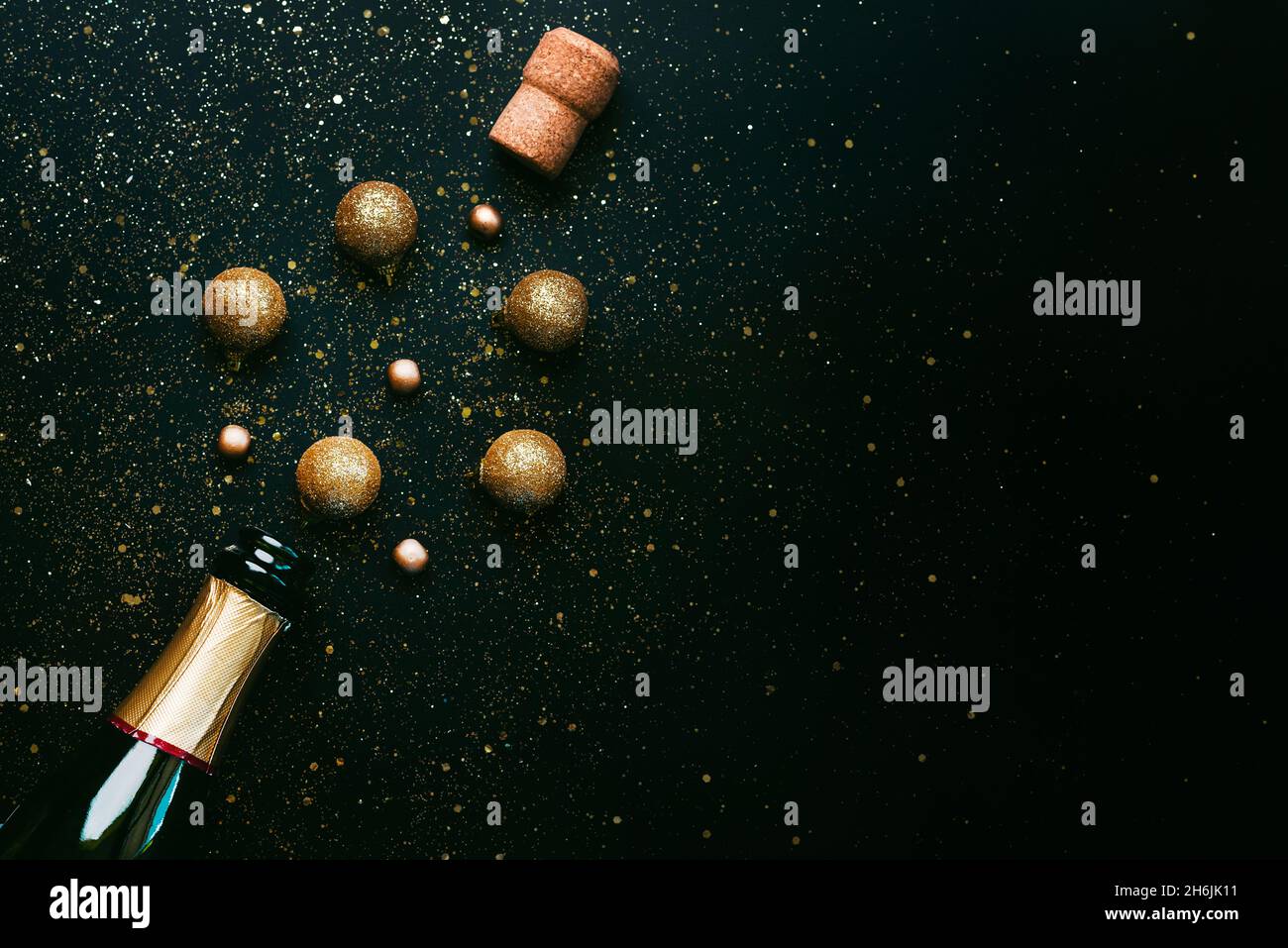 Frohes neues Jahr. Champagner-Flasche und Weihnachtskugeln, glitzernder Glitzer mit Platz für Text auf schwarzem Hintergrund. Silvester Feier Konzept BA Stockfoto