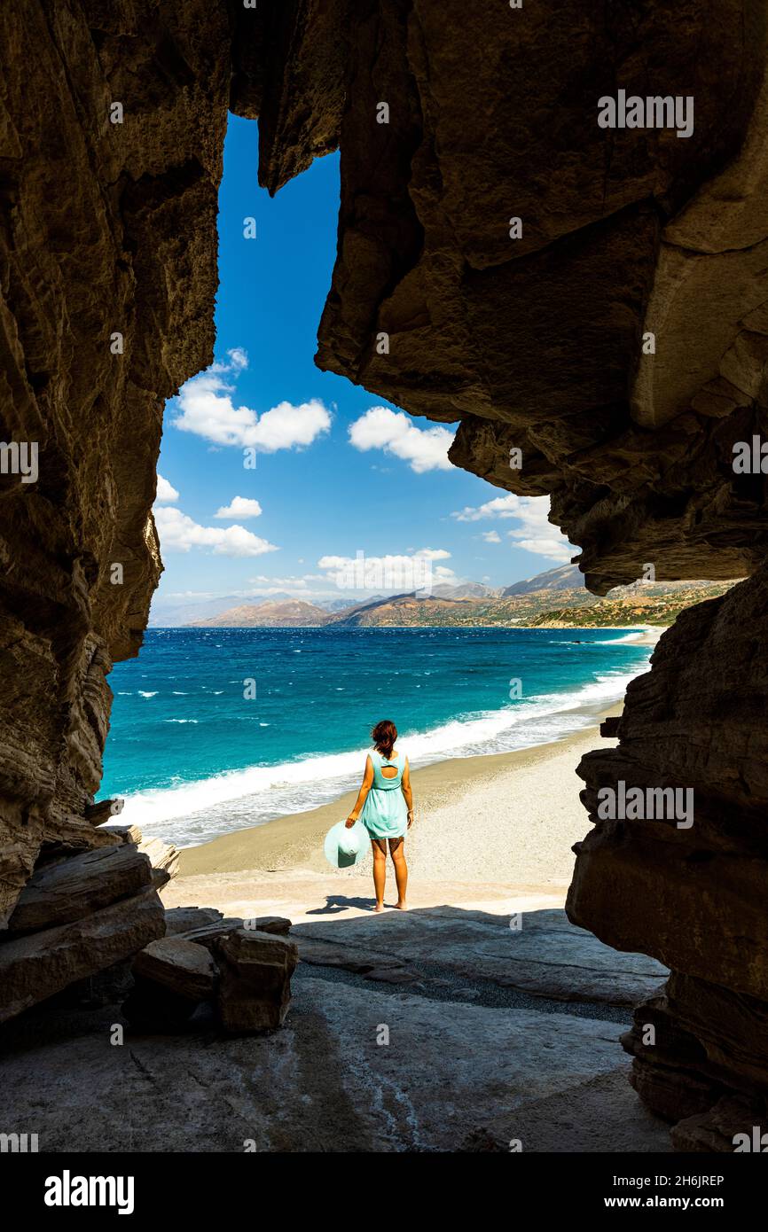 Rückansicht einer jungen Frau, die das kristallklare Meer aus einer natürlichen Höhle am Strand von Triopetra, Plakias, Kreta, griechische Inseln, Griechenland, Europa Stockfoto