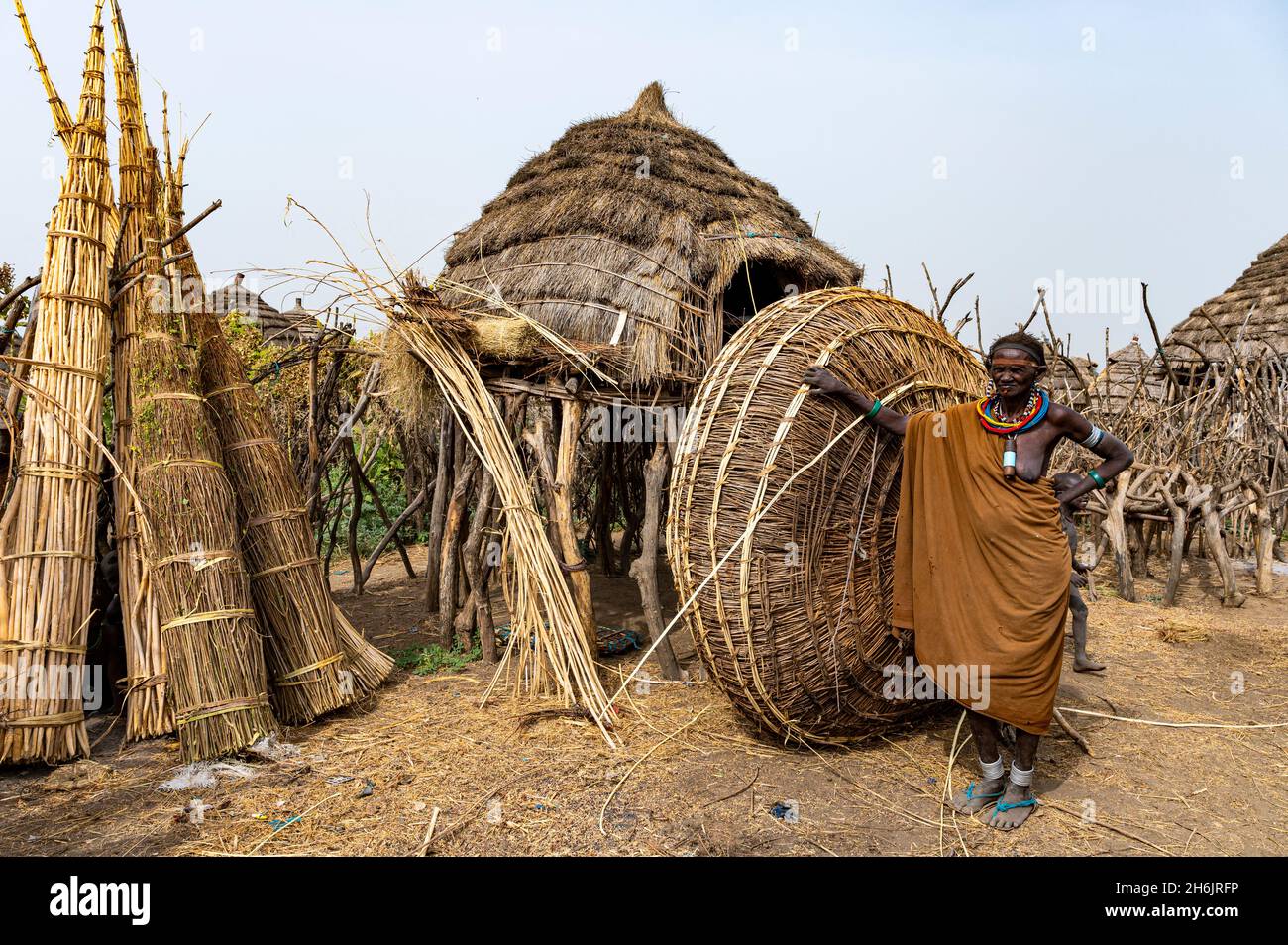 Frau vor ihrer Hütte mit vorbereitetem Schilf, Jiye-Stamm, Staat Eastern Equatoria, Südsudan, Afrika Stockfoto