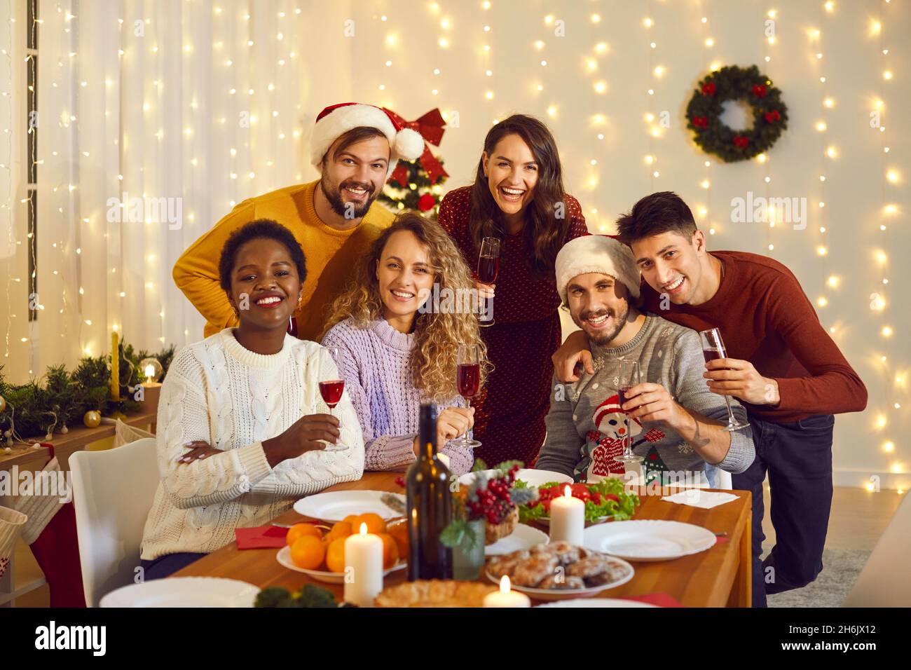 Gruppenportrait von glücklichen, vielfältigen Freunden an einem festlichen Tisch auf der Weihnachtsfeier zu Hause Stockfoto