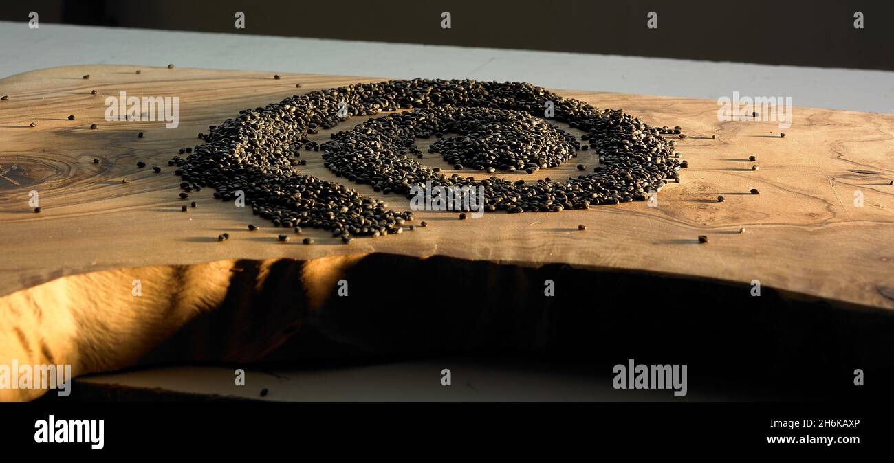 Schwarze Samen bilden ein spiralförmiges Muster auf einem Holzbrett Stockfoto