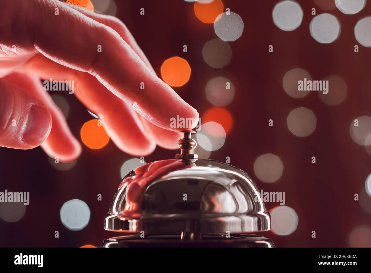 Drücken der Hand auf die Glocke der Hotelrezeption während der Weihnachtszeit, selektiver Fokus Stockfoto