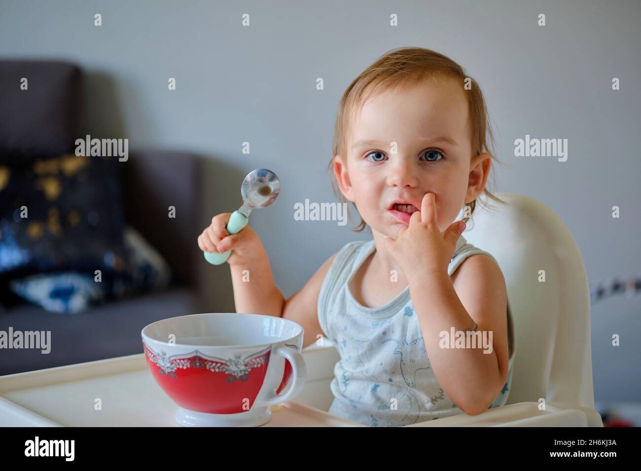 Porträt eines niedlichen kleinen Mädchens, das aus einer Keramikschale Suppe isst und die Kamera anschaut Stockfoto