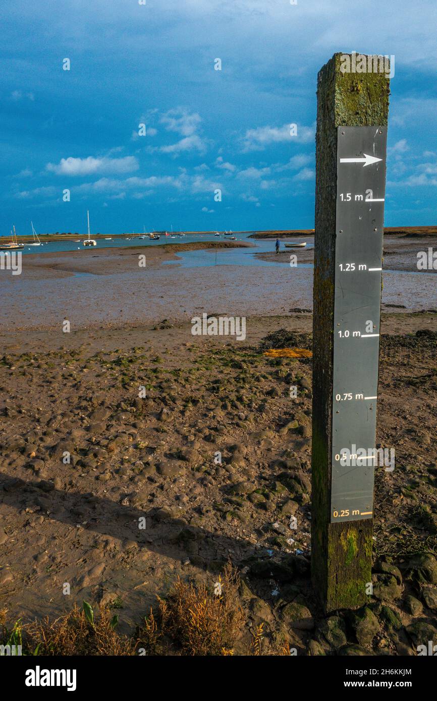 Nahaufnahme einer Tidentiefenmarkierung mit Schlammflatten und Flussmündung im Hintergrund bei Mow Creek Brancaster Staithe Harbour North Norfolk England Stockfoto