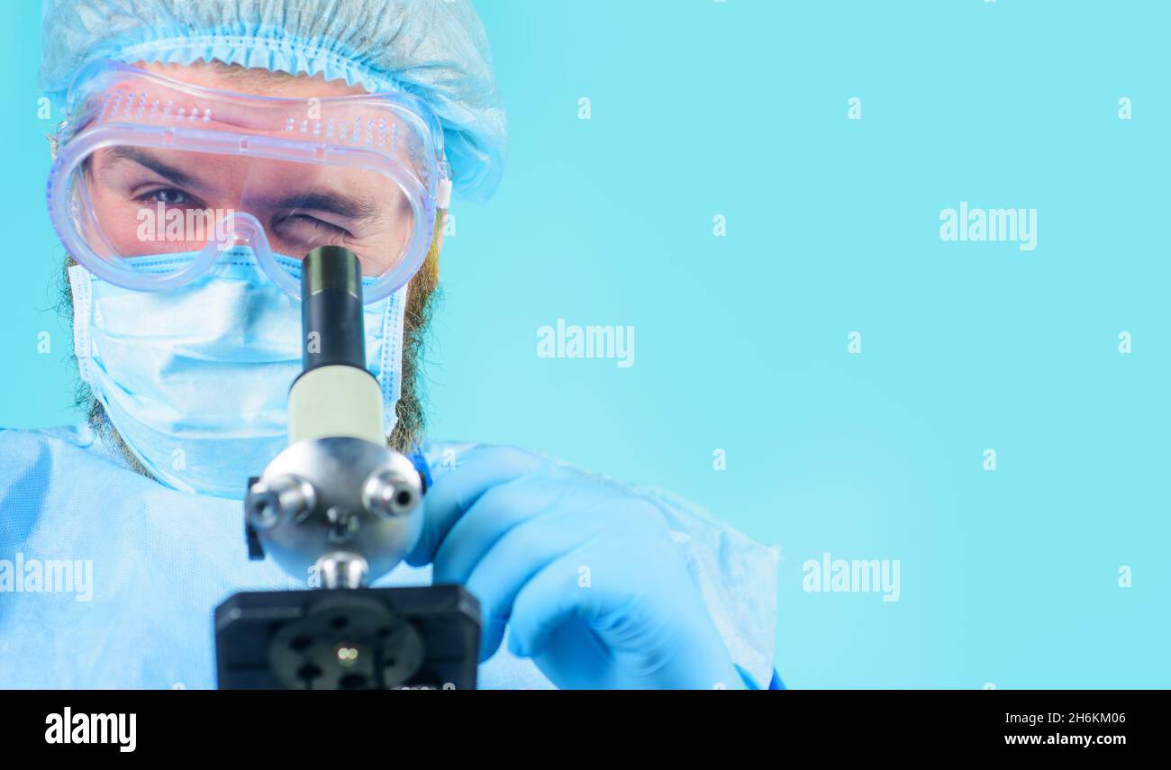 Arzt mit Schutzmaske, Schutzbrille und Handschuhen, die Probe mit dem Mikroskop untersuchen. Wissenschaftler, die im Labor testen oder forschen. Speicherplatz kopieren Stockfoto