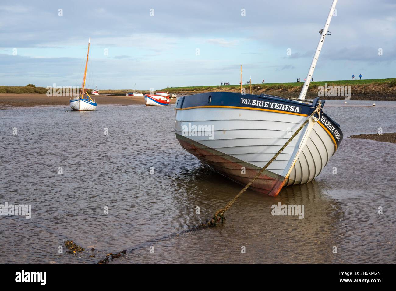 Traditionelle Boote, die bei Ebbe auf Schlammflattern auf dem Fluss Burnham Overy North Norfolk England festgemacht und gesessen haben Stockfoto