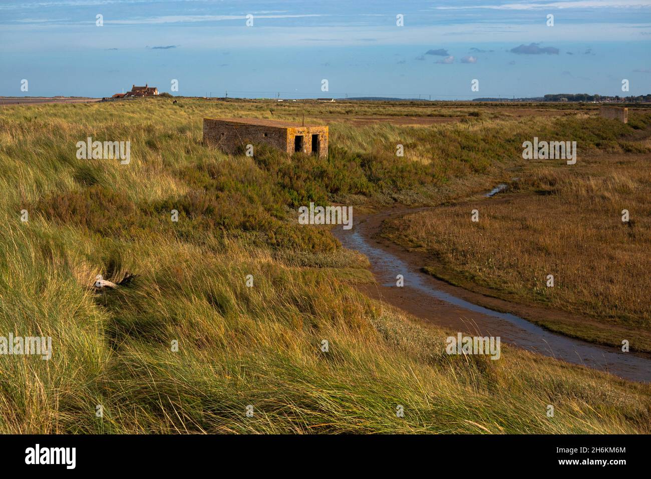 Alte Pillenbox aus dem Zweiten Weltkrieg zwischen den Dünen neben Salzsumpfgebieten am Brancaster Beach im Norden Norfolks in England Stockfoto