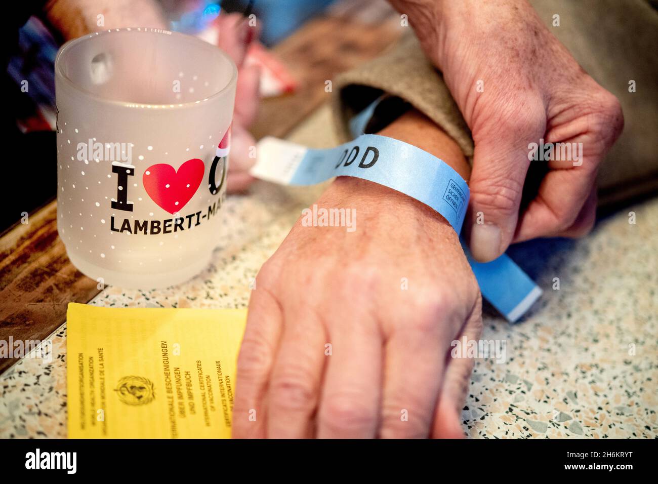 Oldenburg, Deutschland. November 2021. Ein Besucher erhält ein Papierarmband, das für einen Marktbesuch gültig ist, gegen Vorlage des Nachweises über die vollständige Impfung. Der Weihnachtsmarkt im Stadtzentrum wird am 16.11.2021 eröffnet, eine 3G-Verpflichtung gilt. Daher werden am Oldenburger Lamberti-Markt Armbänder verwendet, die die Gäste zum Kauf von Speisen und Getränken berechtigen. Quelle: Hauke-Christian Dittrich/dpa/Alamy Live News Stockfoto