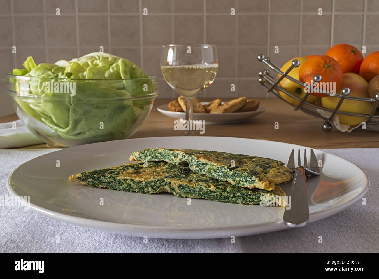 Frittata con spinaci nel piatto con insalata verde Stockfoto