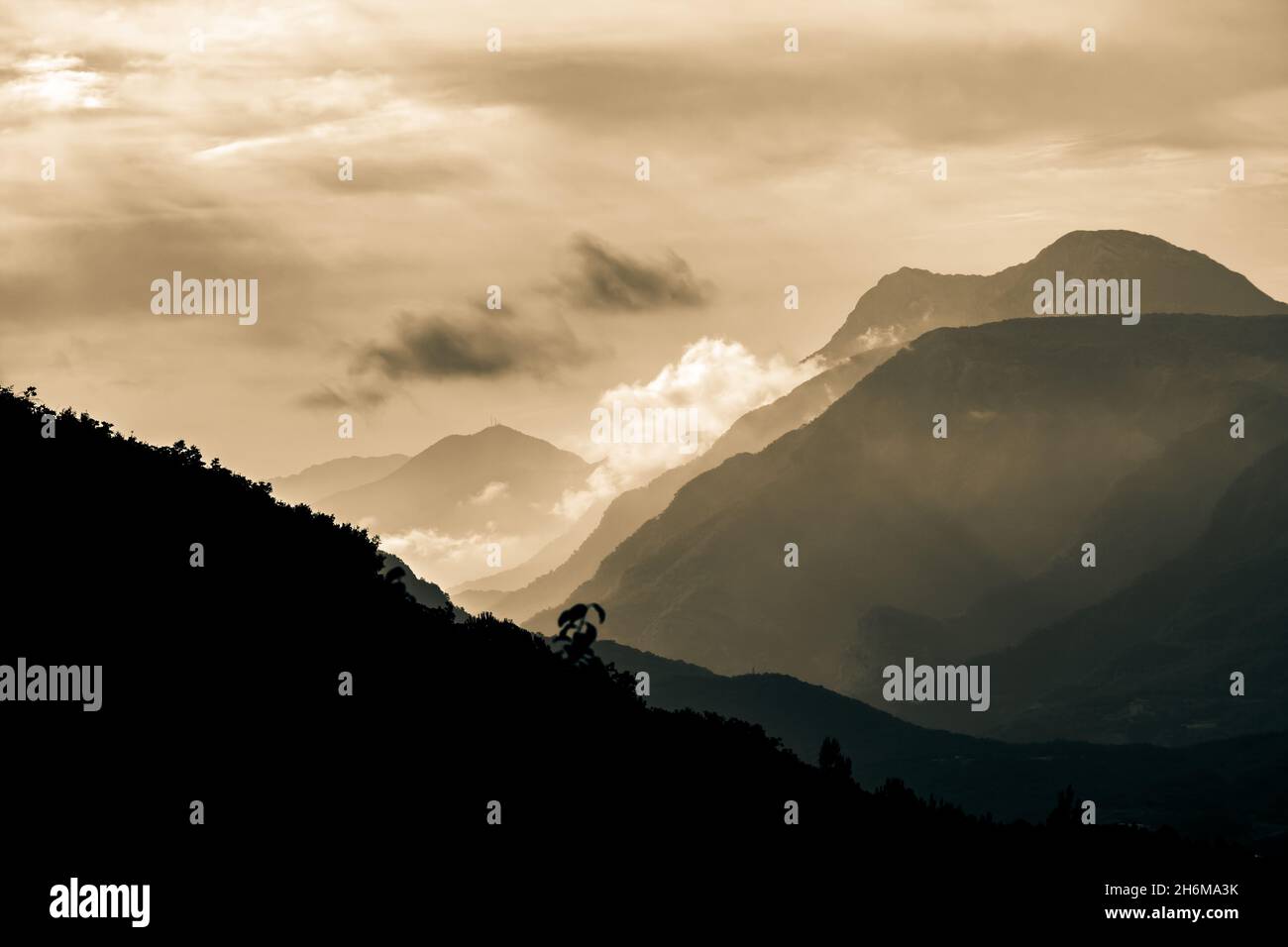 Berggipfel. Sepia-Bergsilhouetten mit Nebel und Nebel. Geschichtete Hügel mit Wolken Hintergrundbild. Stockfoto