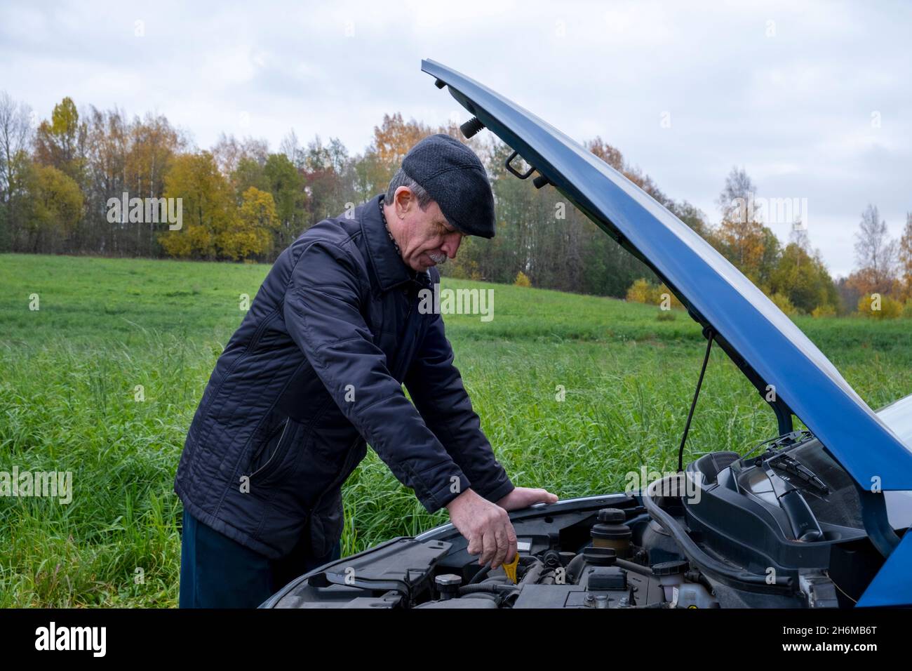 Älterer Mann öffnete die Motorhaube seines Autos und überprüft den Motor auf Probleme Stockfoto