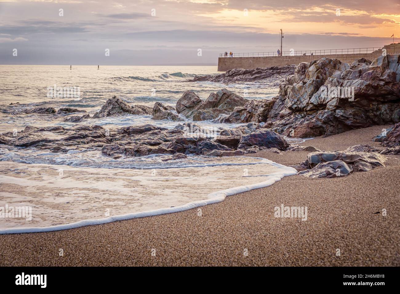 An einem Sommerabend, Porthleven, Cornwall, wirbelt das Meer um Felsen und Pier herum Stockfoto