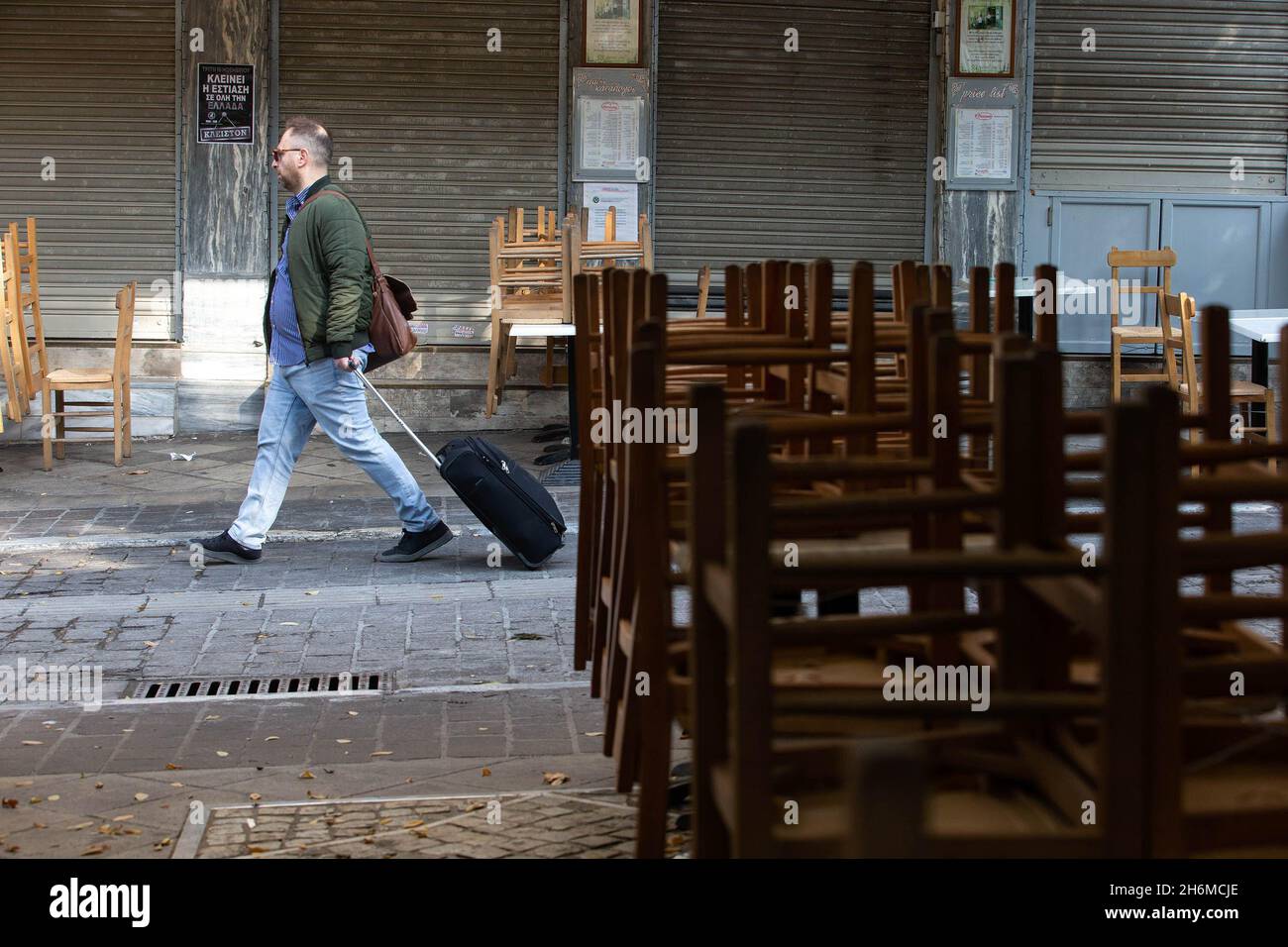 Athen, Griechenland. November 2021. Ein Mann geht am 16. November 2021 an einem geschlossenen Restaurant in Athen, Griechenland, vorbei. Restaurants und Cafés in ganz Griechenland blieben am Dienstag geschlossen, während in Athen eine Demonstration stattfand, in der weitere staatliche Unterstützung im Rahmen der neuen COVID-19-Beschränkungen gefordert wurde, die von der Regierung im Herbst dieses Jahres eingeführt wurden, um den jüngsten Anstieg der Infektionsraten zu bekämpfen. Quelle: Marios Lolos/Xinhua/Alamy Live News Stockfoto
