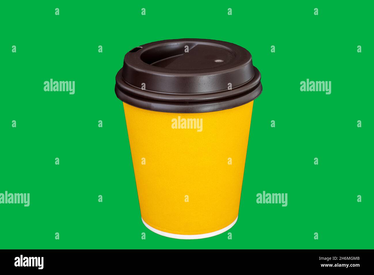 Gelbe Papiertasse für Kaffee oder Tee. Pappbecher auf isoliertem grünem Hintergrund Stockfoto
