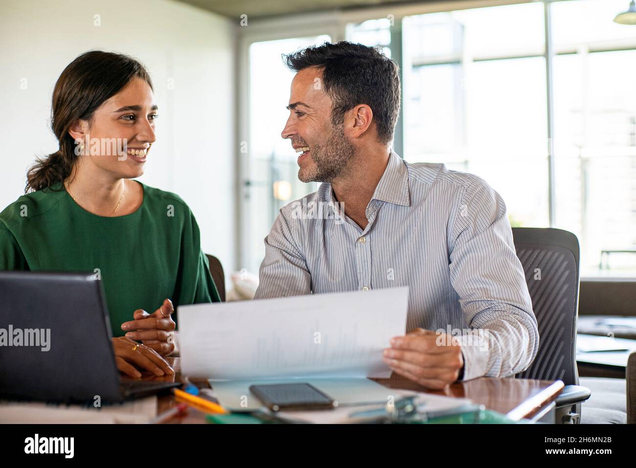 Lächelnde junge Frau und reifer Mann, der im Büro arbeitet Stockfoto