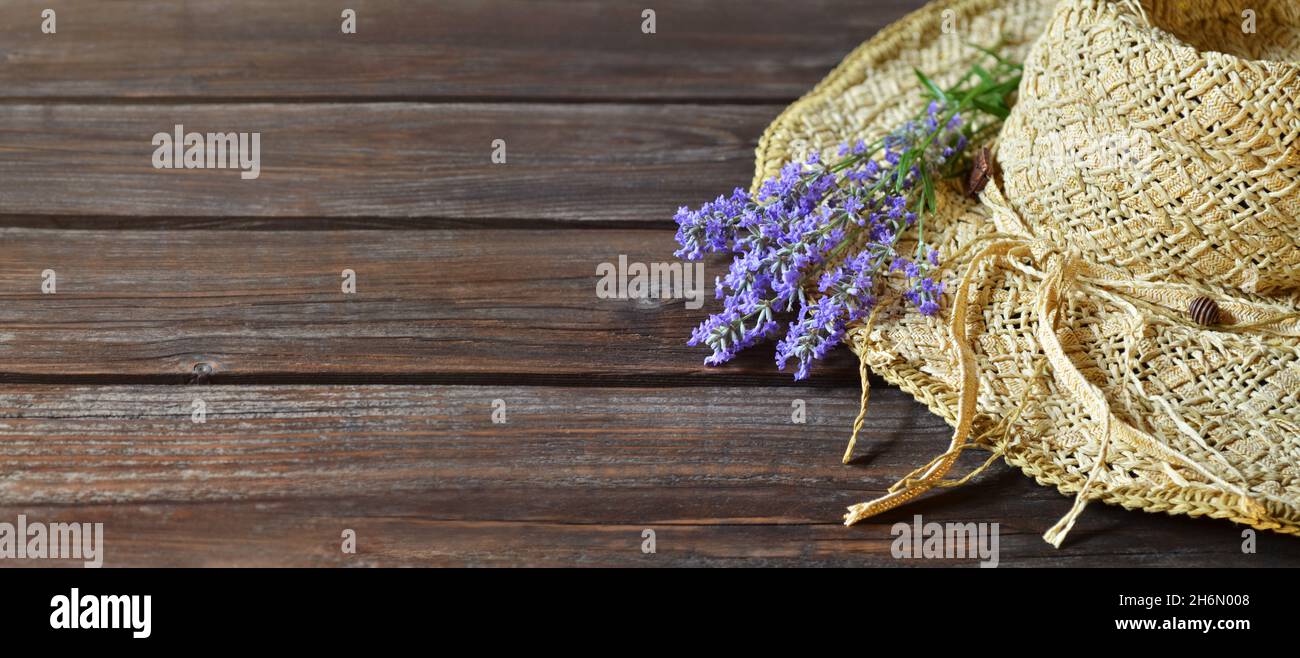 Korbhut mit Strauß lila Lavendelblüten auf einem Holztisch mit einem Kopierraum. Sommerkomposition. Stockfoto
