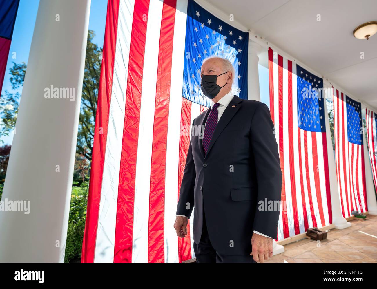 Präsident Joe Biden geht am Montag, den 15. November 2021, entlang der Kolonnade des Weißen Hauses an drapierten amerikanischen Flaggen vorbei, auf dem Weg zur Residenz. (Offizielles Foto des Weißen Hauses von Adam Schultz) Stockfoto