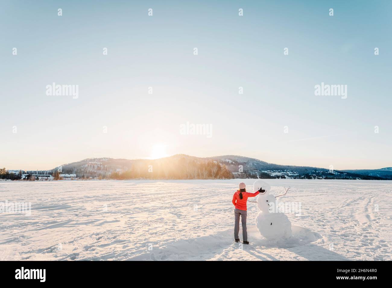 Winteraktivitäten. Frau macht Schneemann im Winter See Schnee Natur Landschaft Stockfoto
