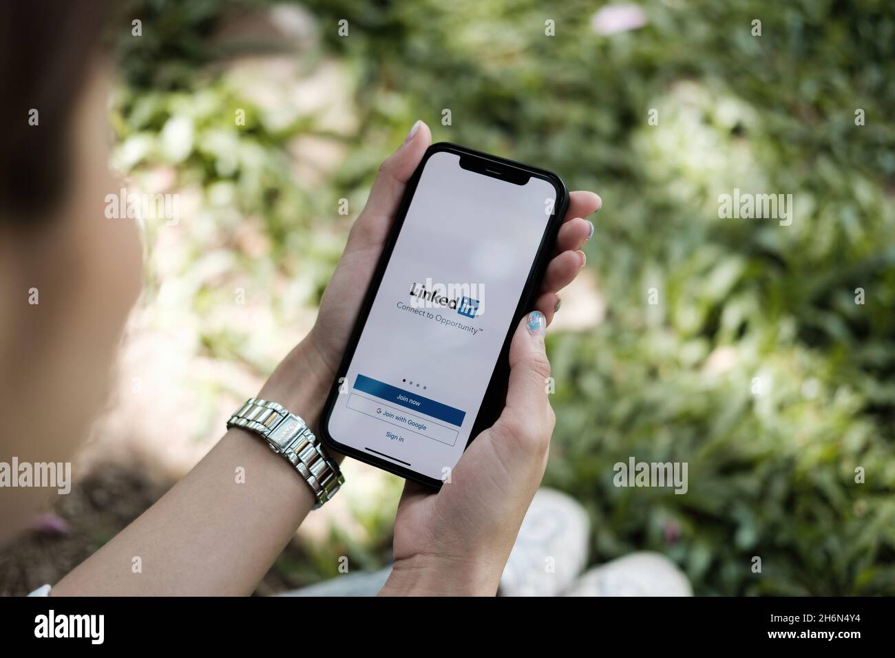 CHIANG MAI, THAILAND OCT 3, 2021 : Eine Frau, die ein iPhone x mit dem sozialen Netzwerkdienst LinkedIn auf dem Bildschirm hält. IPhone 6s wurde erstellt und entwickelt Stockfoto