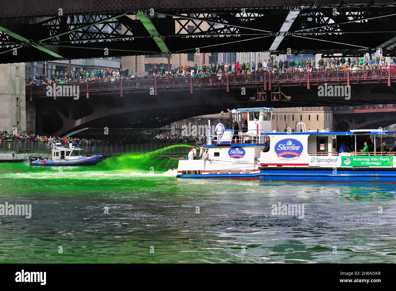 Chicago, Illinois, USA. Die Menschen säumen die State Street und andere Brücken entlang des Chicago River, um den Crews zuzusehen, die den Chicago River grün färben. Stockfoto