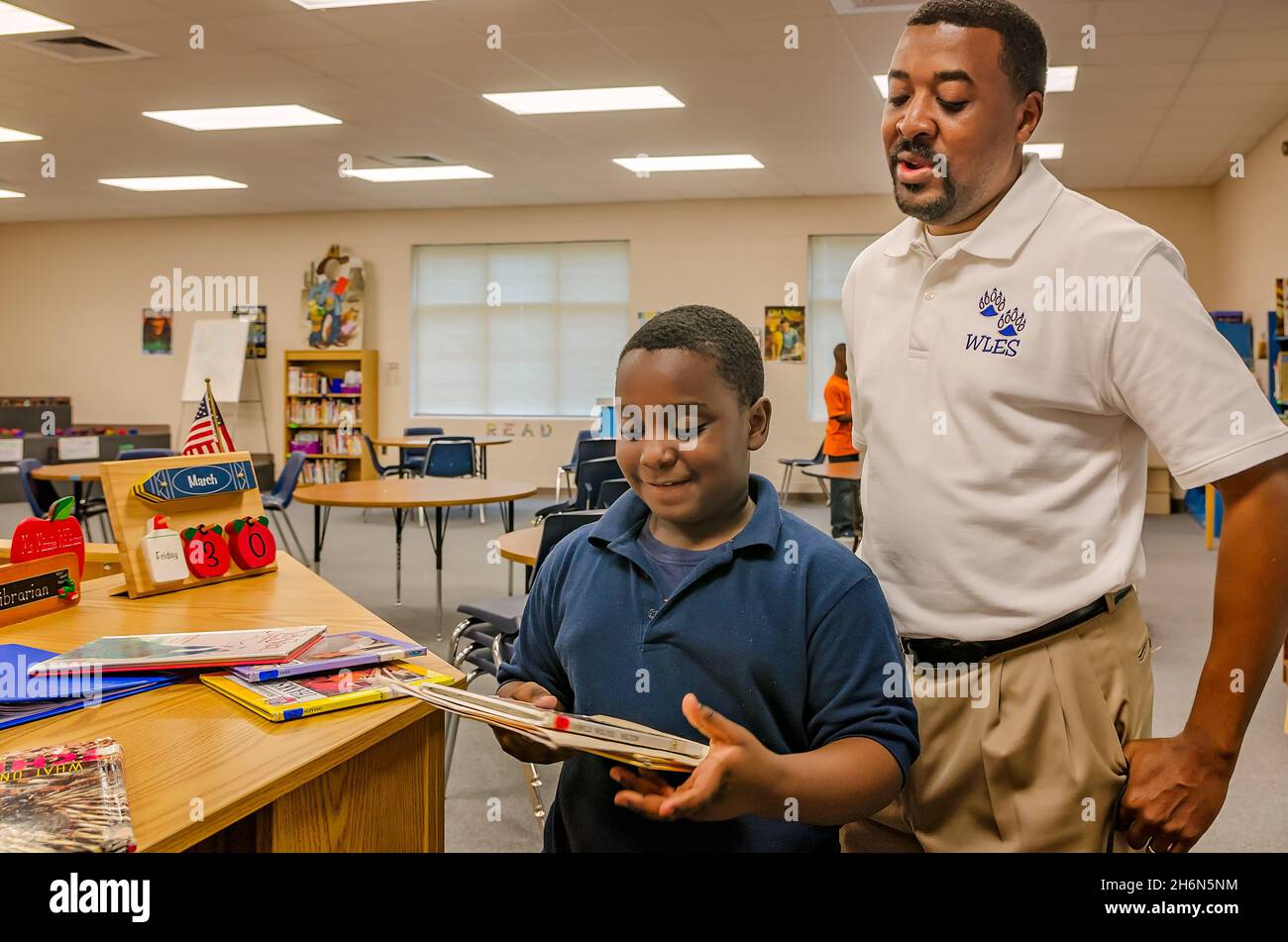 Ein männlicher Lehrer hilft einem Grundschüler, Bibliotheksbücher in der Schulbibliothek am 4. Oktober 2011 in Columbus, Mississippi, auszuwählen. Stockfoto