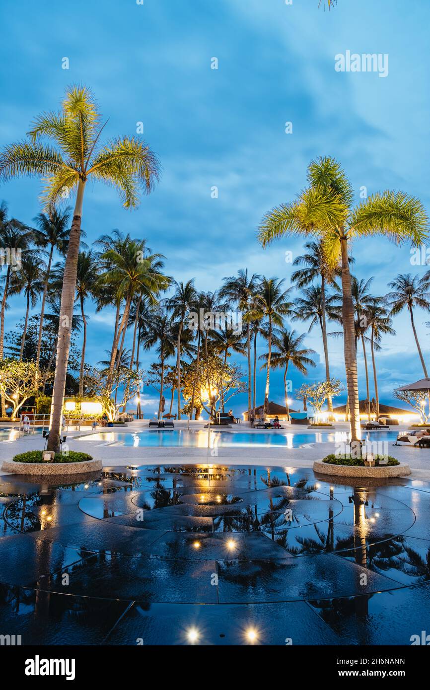 Palmen und Schwimmbad des Luxus-Resorts in Asien. Palmen während des Sonnenuntergangs Stockfoto