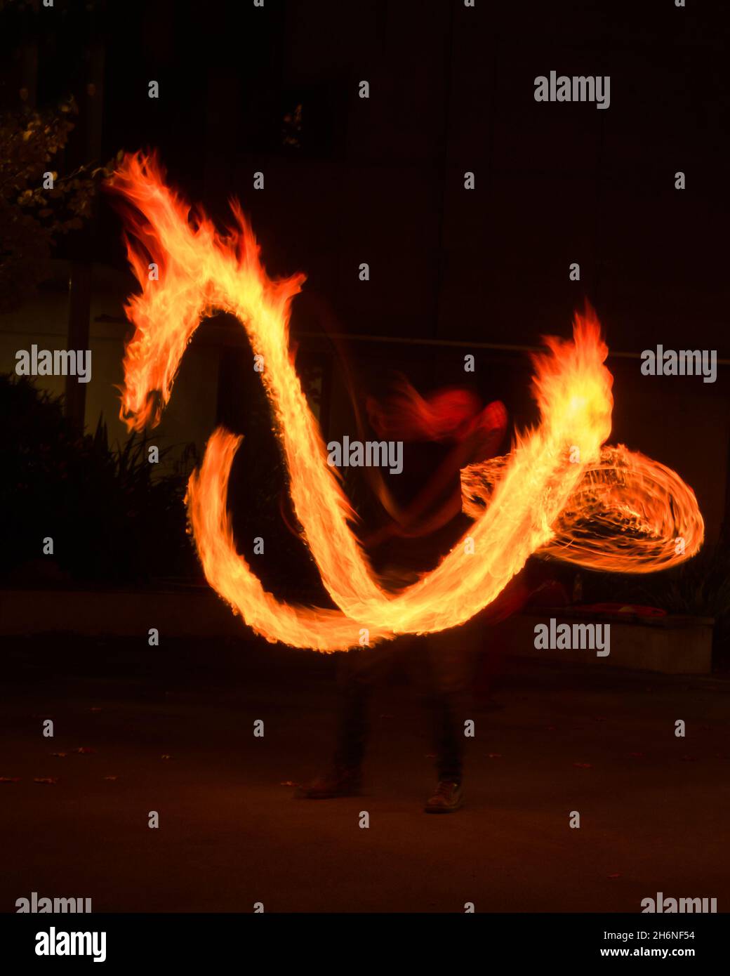 Künstler jongliert mit brennenden Poi bei Feuervorstellung. Langzeitbelichtung Bild der abstrakten Feuer Licht Malerei. Vertikales Format. Stockfoto