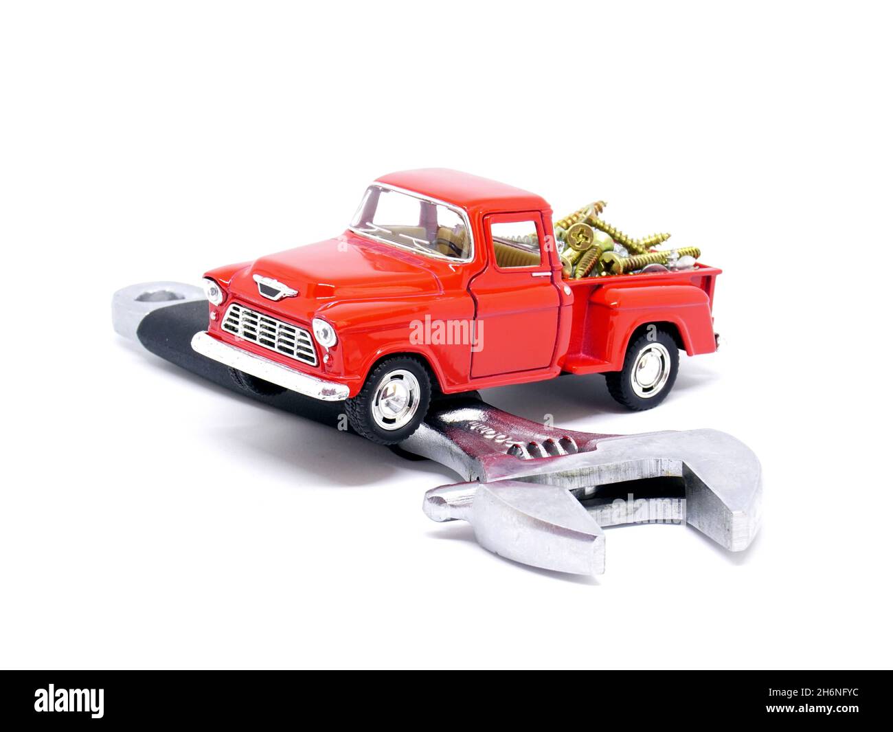 Roter Spielzeugabnehmer und verstellbarer Schraubenschlüssel auf weißem Hintergrund. Reparaturkonzept für das Auto Stockfoto