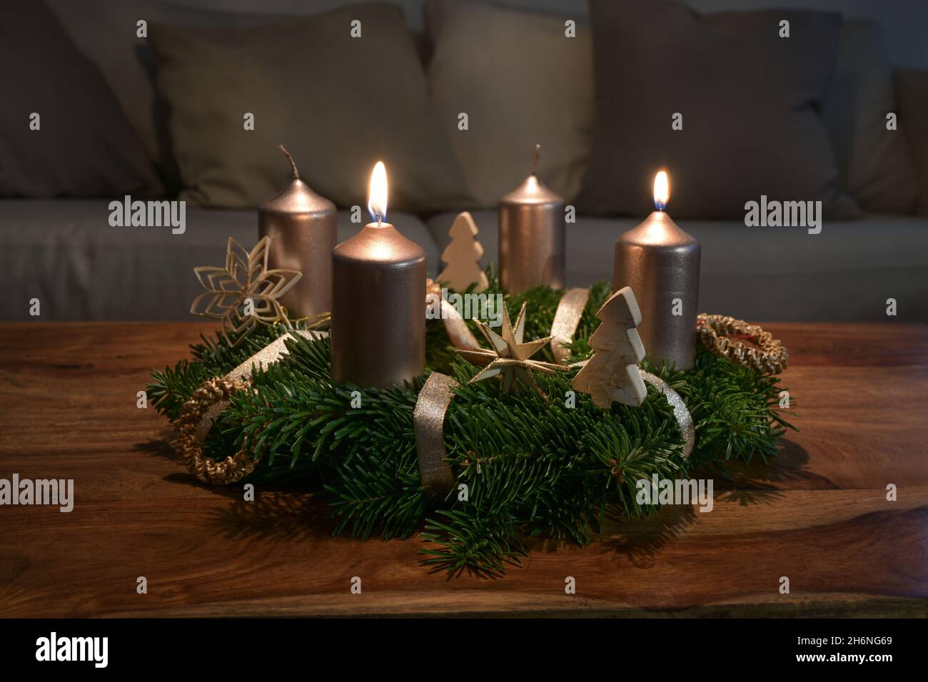 Zwei goldene Kerzen werden für den zweiten Sonntag auf einem Adventskranz mit natürlicher Weihnachtsdekoration auf einem hölzernen Couchtisch angezündet, Kopierfläche, ausgewählt f Stockfoto