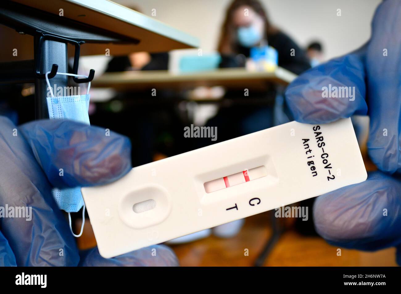 FOTOMONTAGE, positiver Antigen-Schnelltest, Gesichtsmaske hängt am Studierendentisch, Präsenzunterricht, Corona-Krise, Stuttgart, Baden-Württemberg Stockfoto