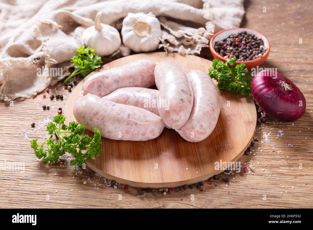 Frische Würstchen mit Gewürzen und Gemüse auf einem Holzbrett Stockfoto