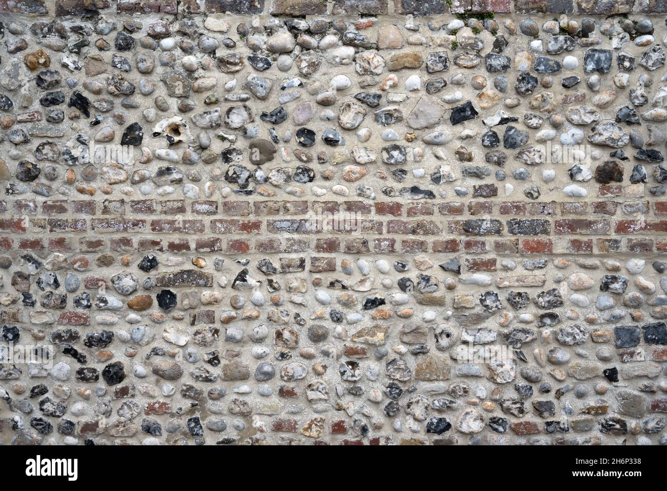 Detailreiche Aufnahme eines alten Steinwalles mit einer Mischung aus Ziegeln und Pflastersteinen. Verwendbar als Hintergrund oder Textur. Stockfoto