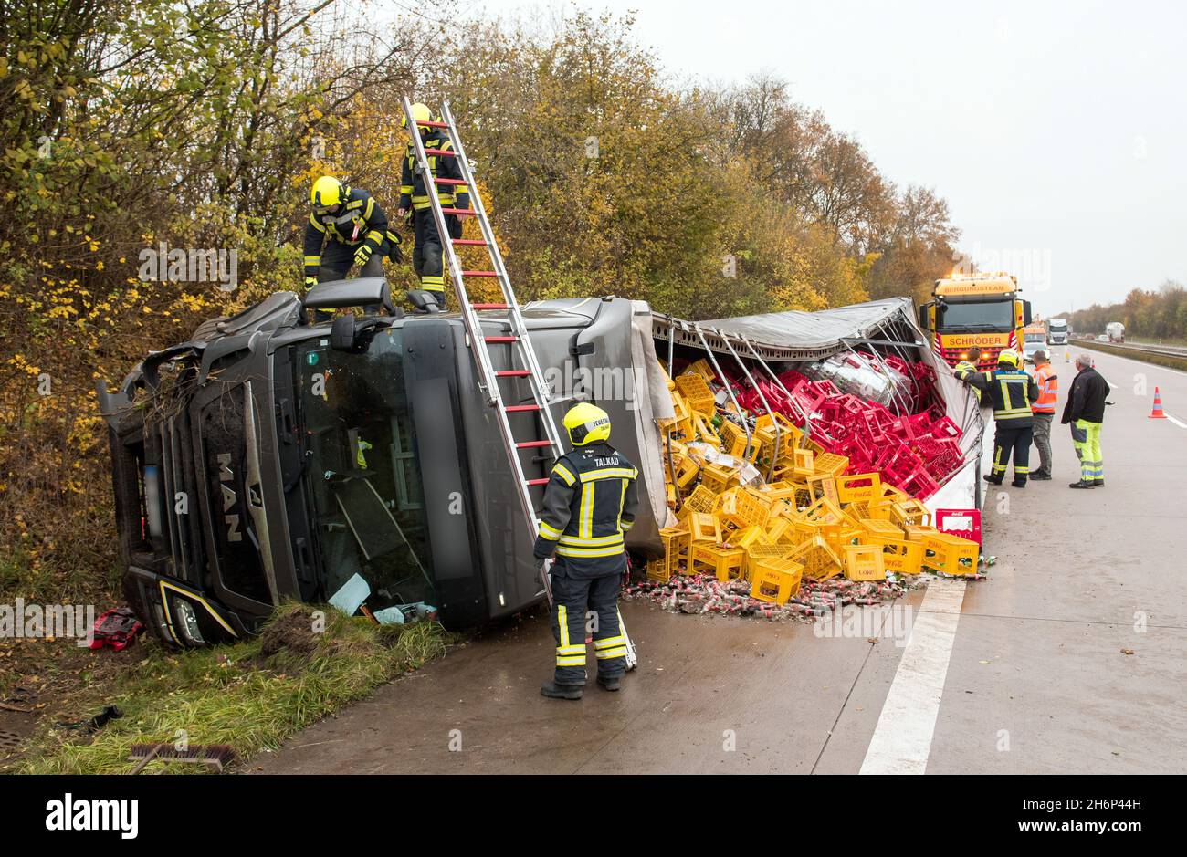 Talkau, Deutschland. November 2021. Rettungsdienste stehen auf und in der Nähe eines umgedrehten Getränkehauses am Unfallort auf der Autobahn A24. Der Lastwagen hatte die Fahrbahn am Morgen verlassen und umgestrostet, wobei er seine Last auf die Fahrbahn streute. (To dpa 'Truck loaded with crates of drinks overturns on motorway') Quelle: Daniel Bockwoldt/dpa/Alamy Live News Stockfoto