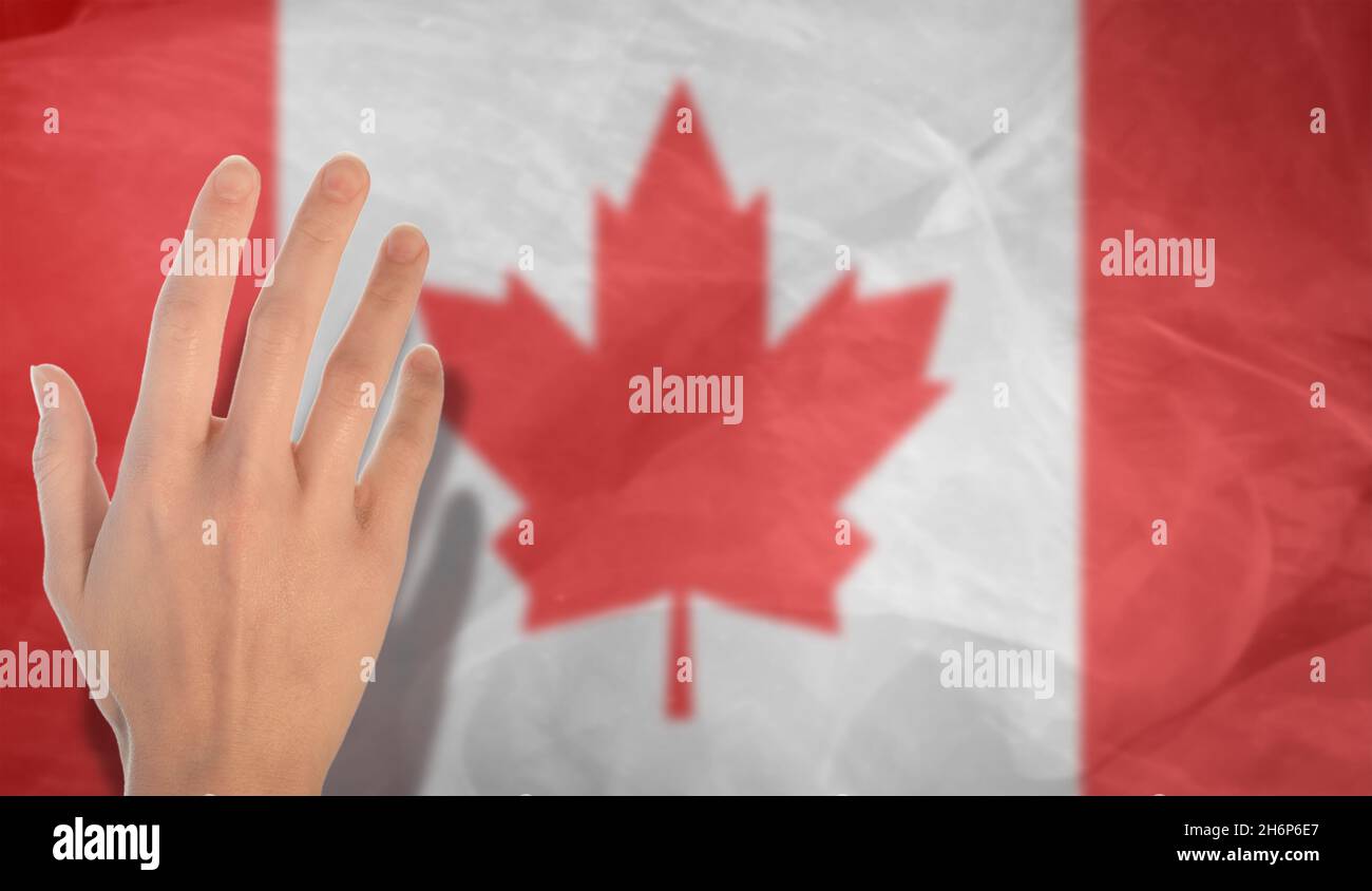 Eine Frauenhand auf dem Hintergrund der Nationalflagge Kanadas. Eine Geste mit erhobener Hand vor dem Hintergrund der kanadischen Flagge. Stockfoto