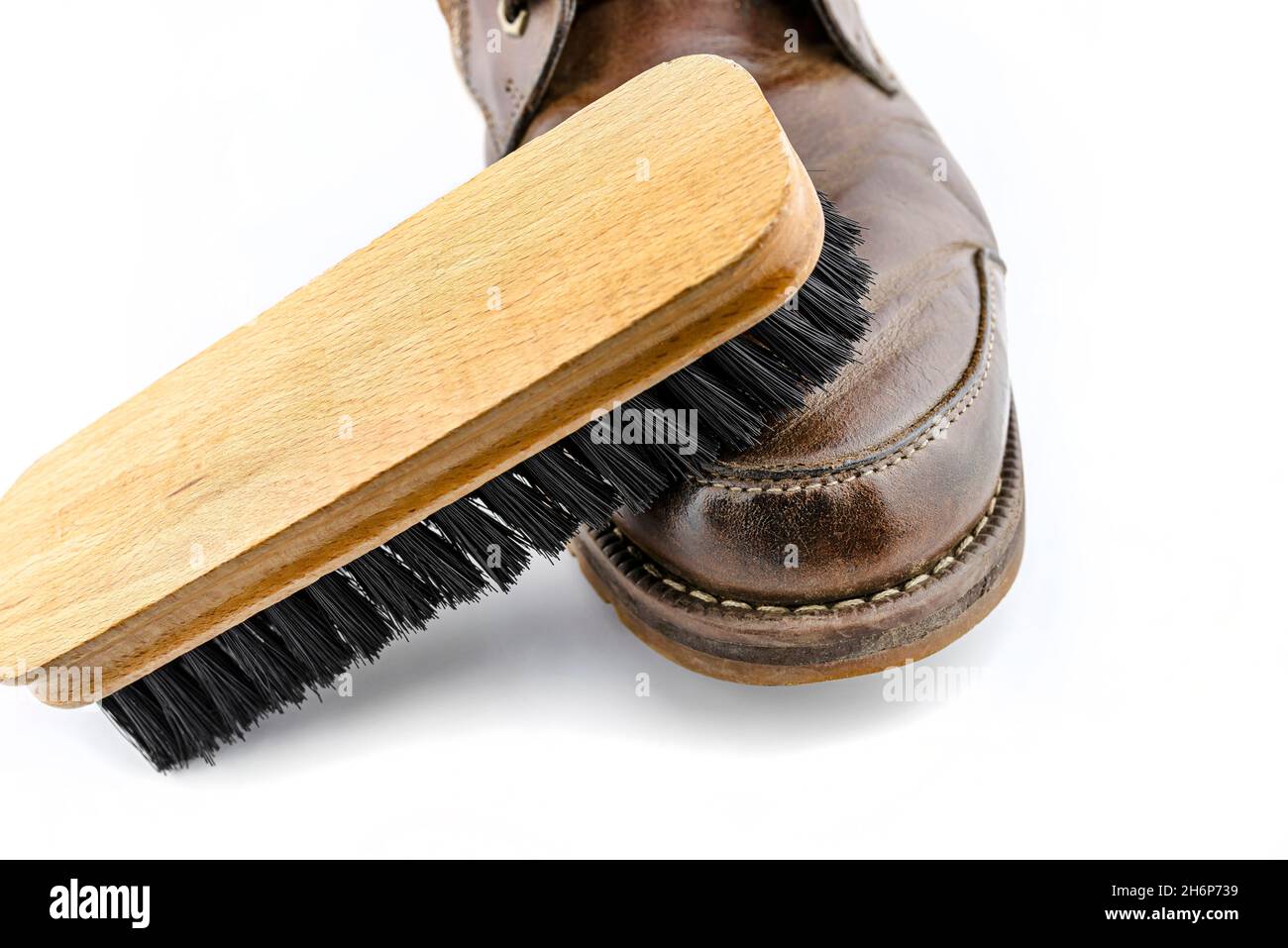 Alte braune Lederschuhe mit Paste poliert, Schuhbürste liegt auf dem Schuh, isoliert auf weißem Hintergrund. Stockfoto