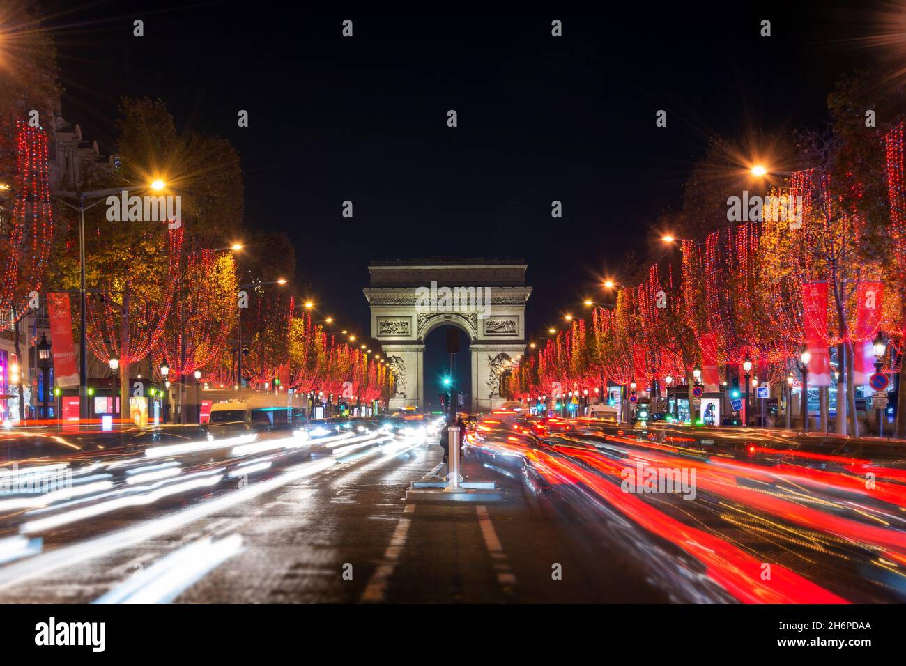 Die Champs Elysees Avenue und der Triumphbogen sind nachts in Paris, Frankreich, mit roten Weihnachtslichtern geschmückt. Weihnachtsferien, Winter in Paris. Stockfoto