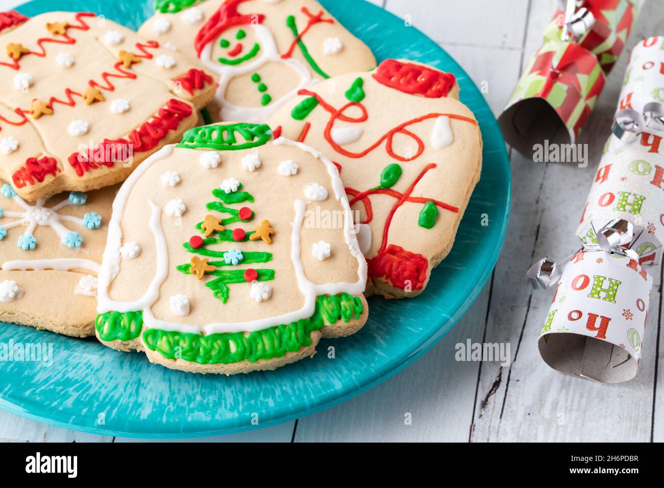 Rechts ein Teller mit hässlichen Weihnachts-Pullover-Keksen mit festlichen Crackern. Stockfoto